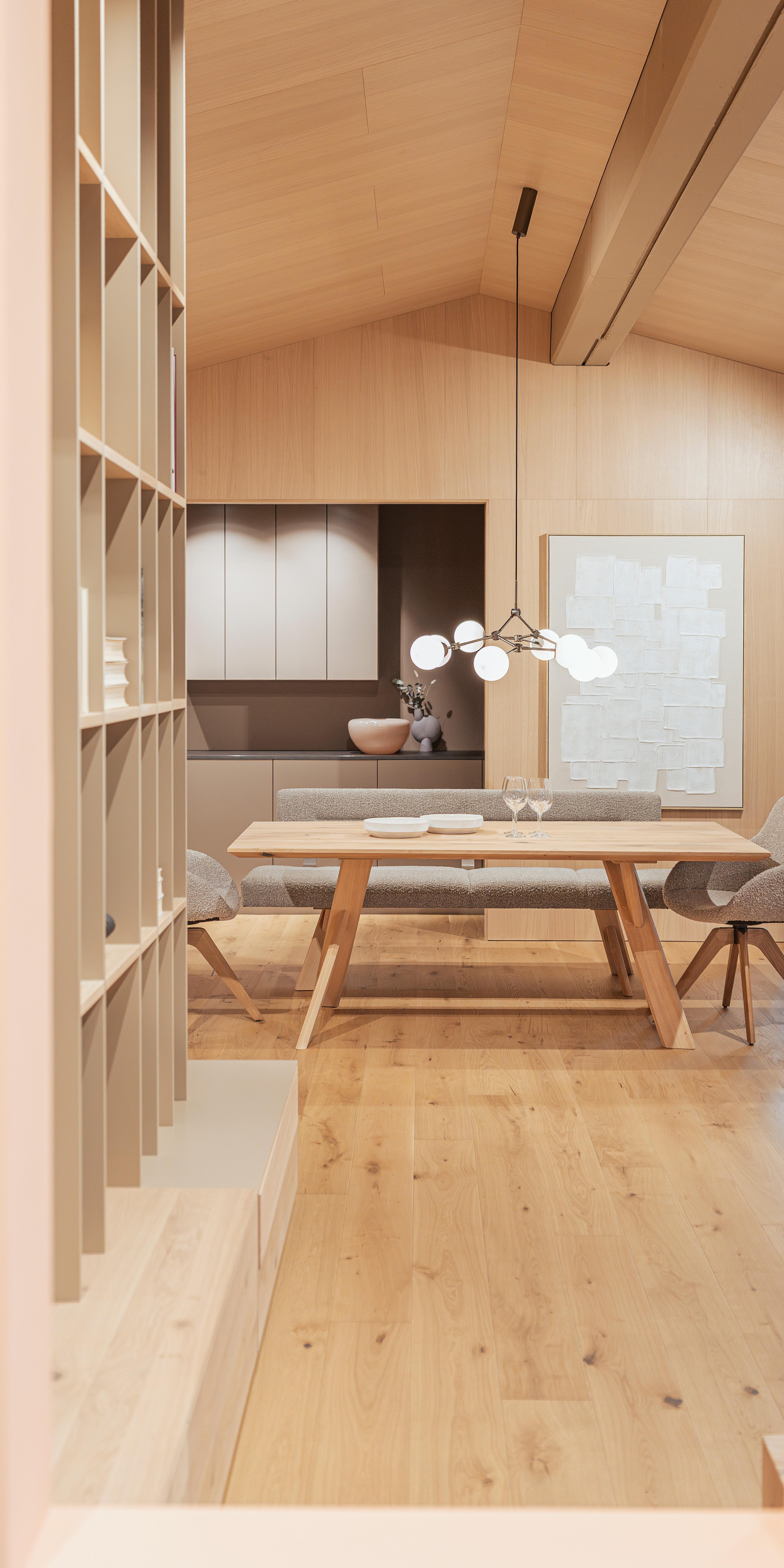 Helles Esszimmer mit Holztisch, Stühlen und modernem Kronleuchter.