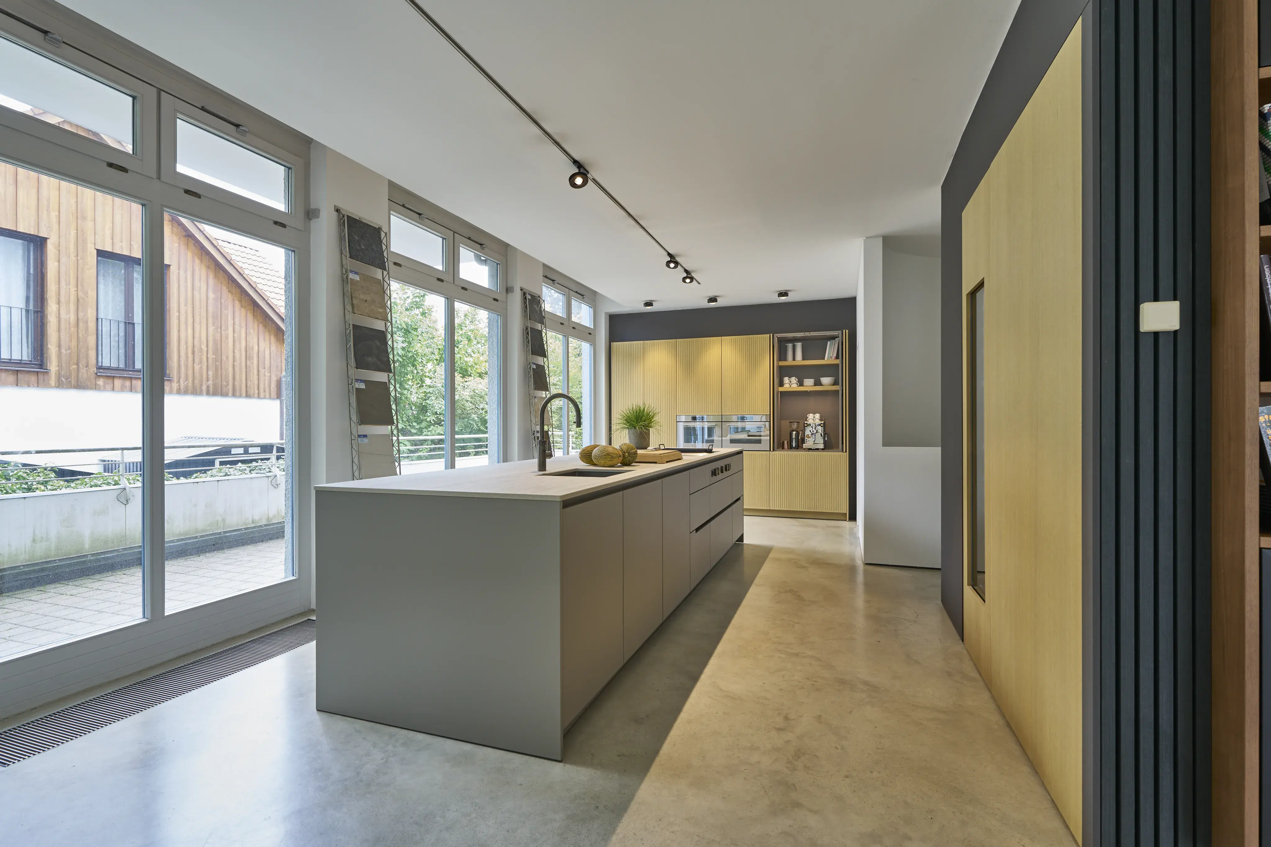 Moderne, helle Küche mit großer Kochinsel, viel Tageslicht und minimalistischer Einrichtung.