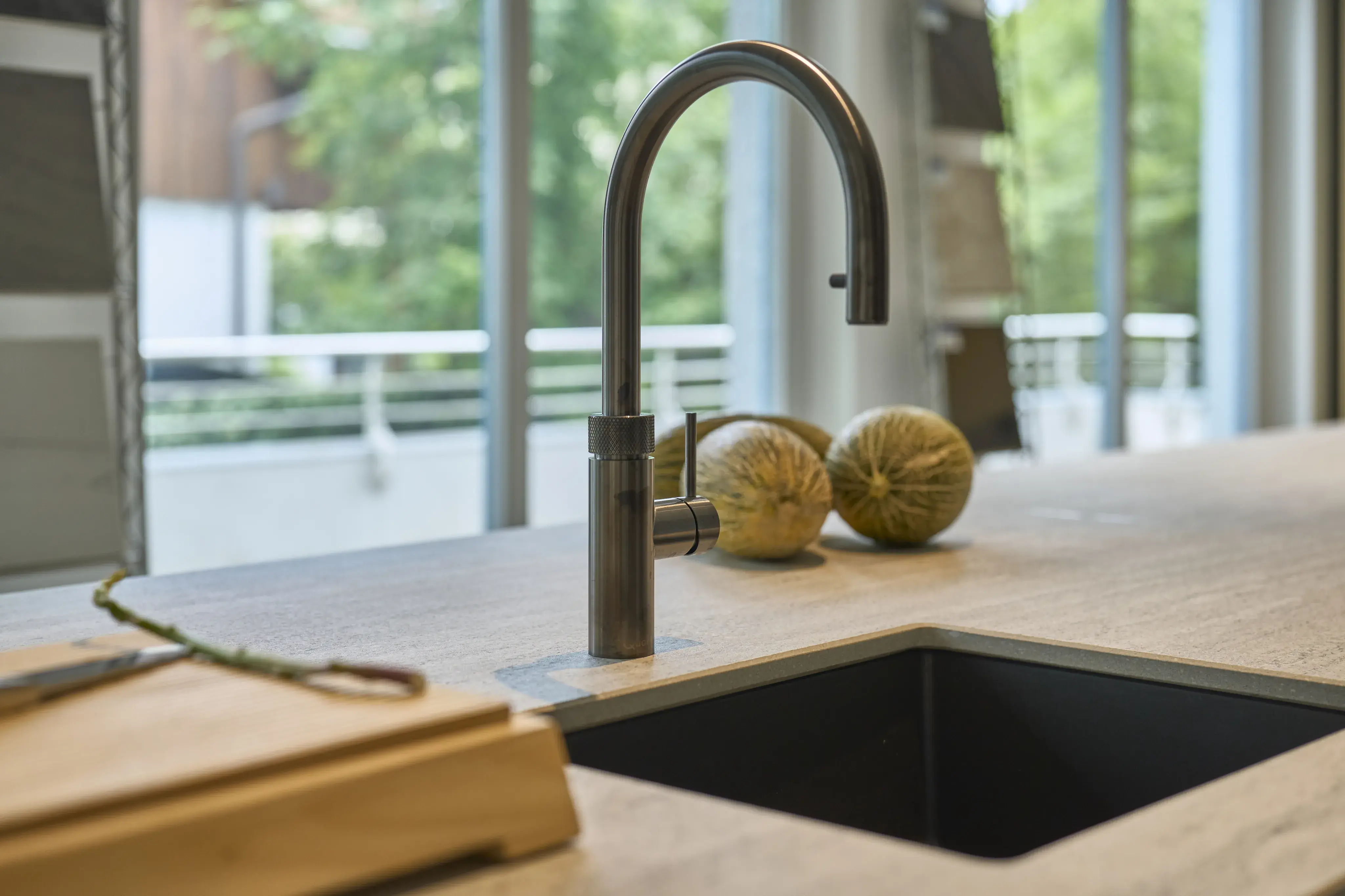 Moderne Küchenspüle mit Wasserhahn, zwei Kürbisse auf der Arbeitsplatte.