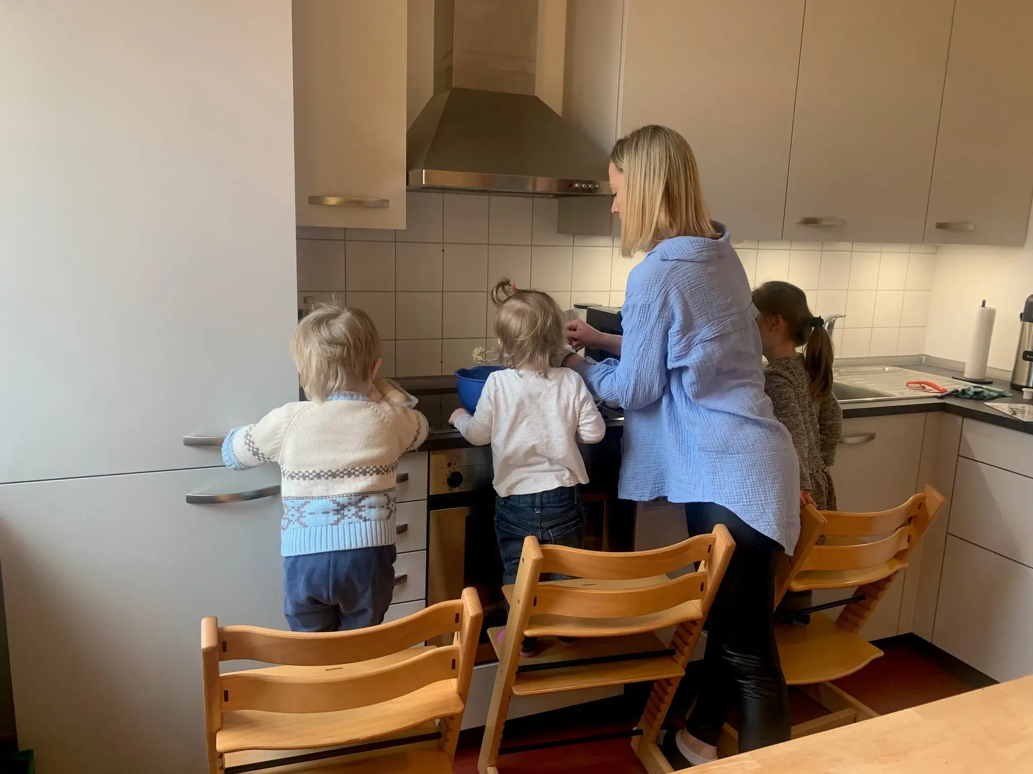 Zwei Kinder mit einer Frau in einer Küche